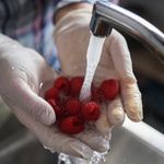 Manos enguantadas lavándose en un fregadero como parte de las buenas prácticas de higiene en seguridad alimentaria.